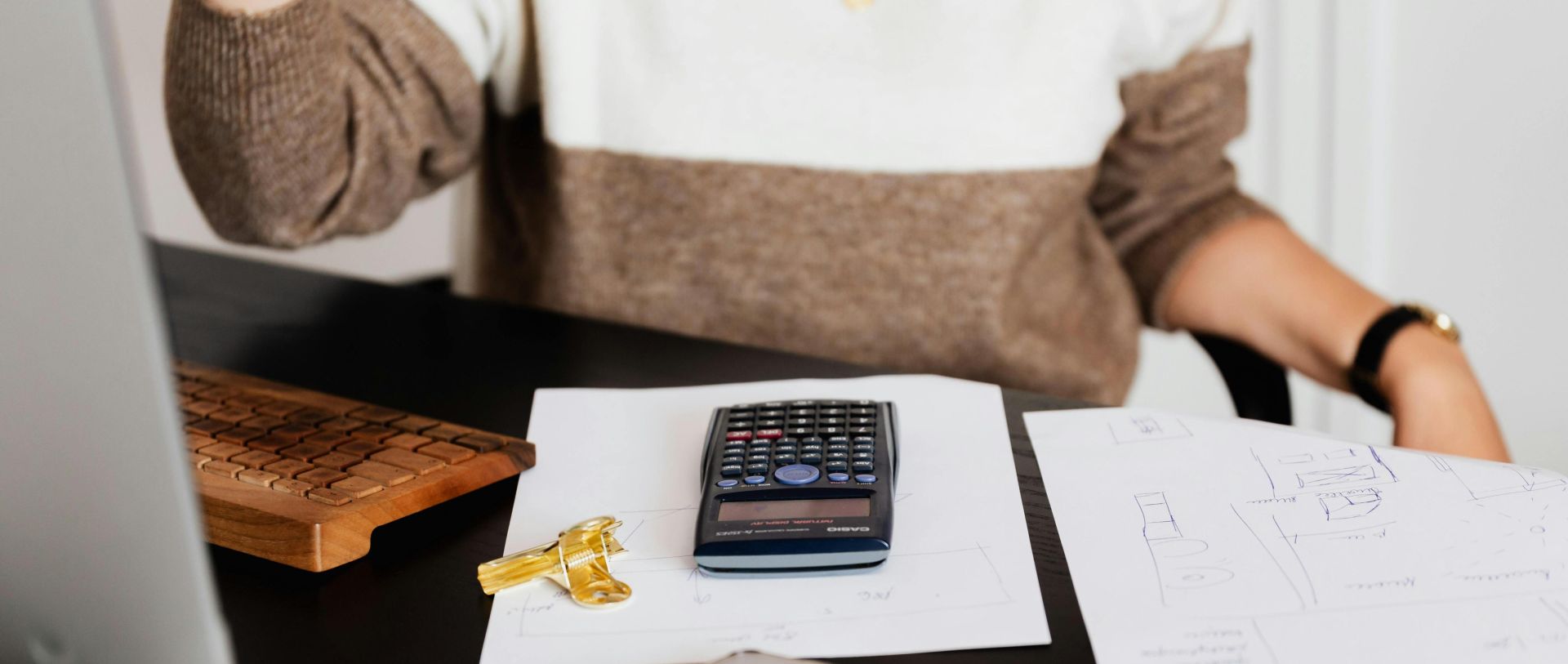 A business desk setup with a calculator, papers, and a keyboard, reflecting a work environment.